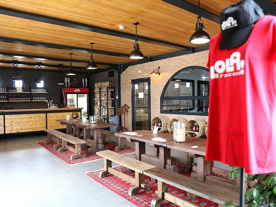 Pineios Brewery tasting room, wood tables with benches and a mannequin dressed with a red T-shirt that said Lola